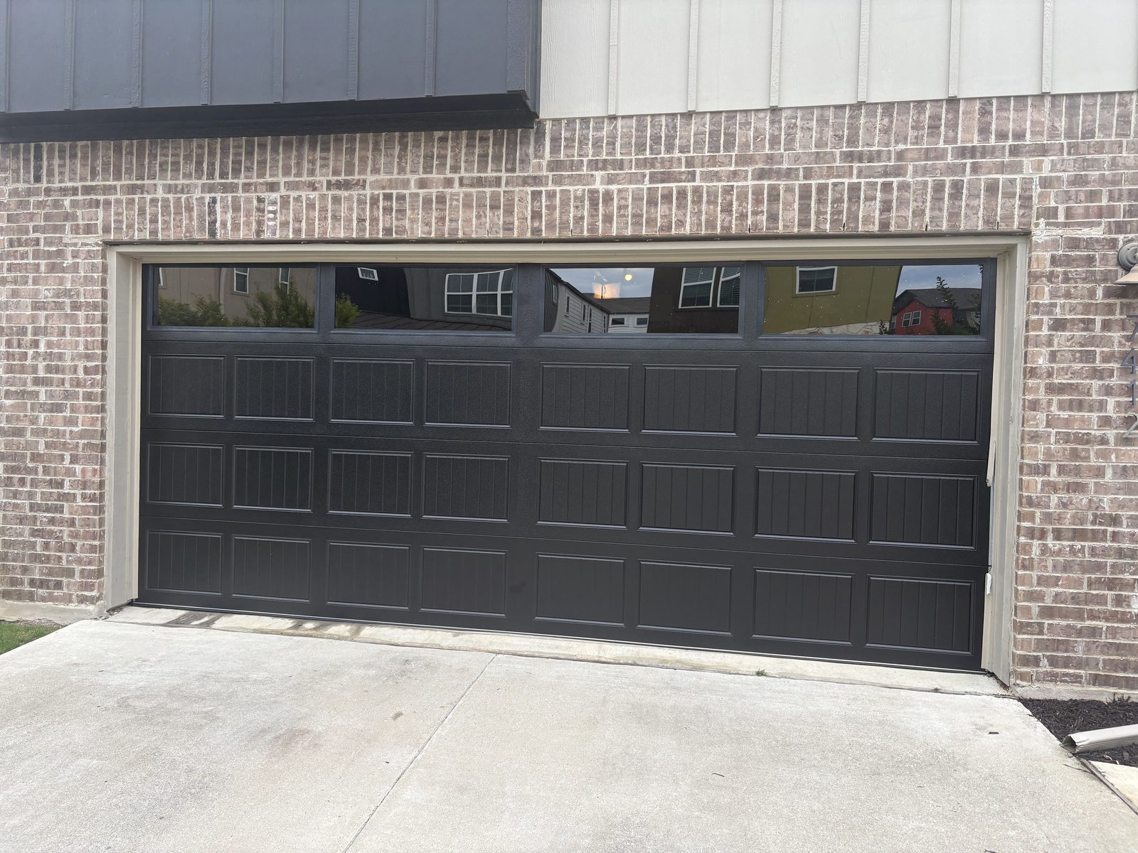 Newly installed garage door with window panels on an Austin, TX home after replacement