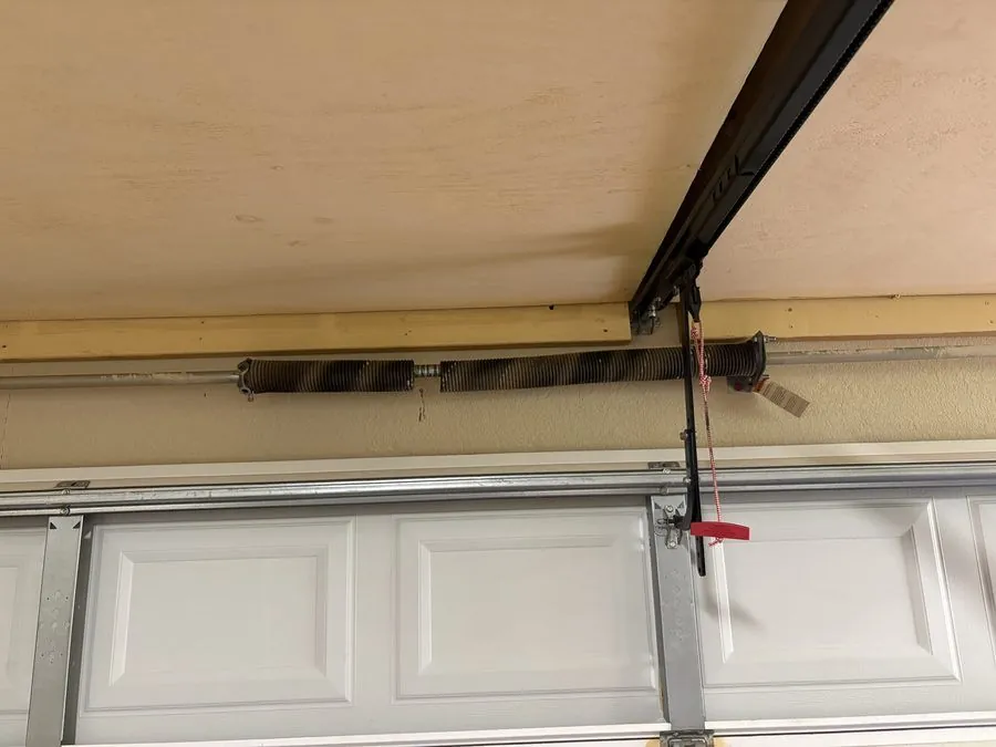 Torsion spring system on garage door, visible gap indicates broken spring