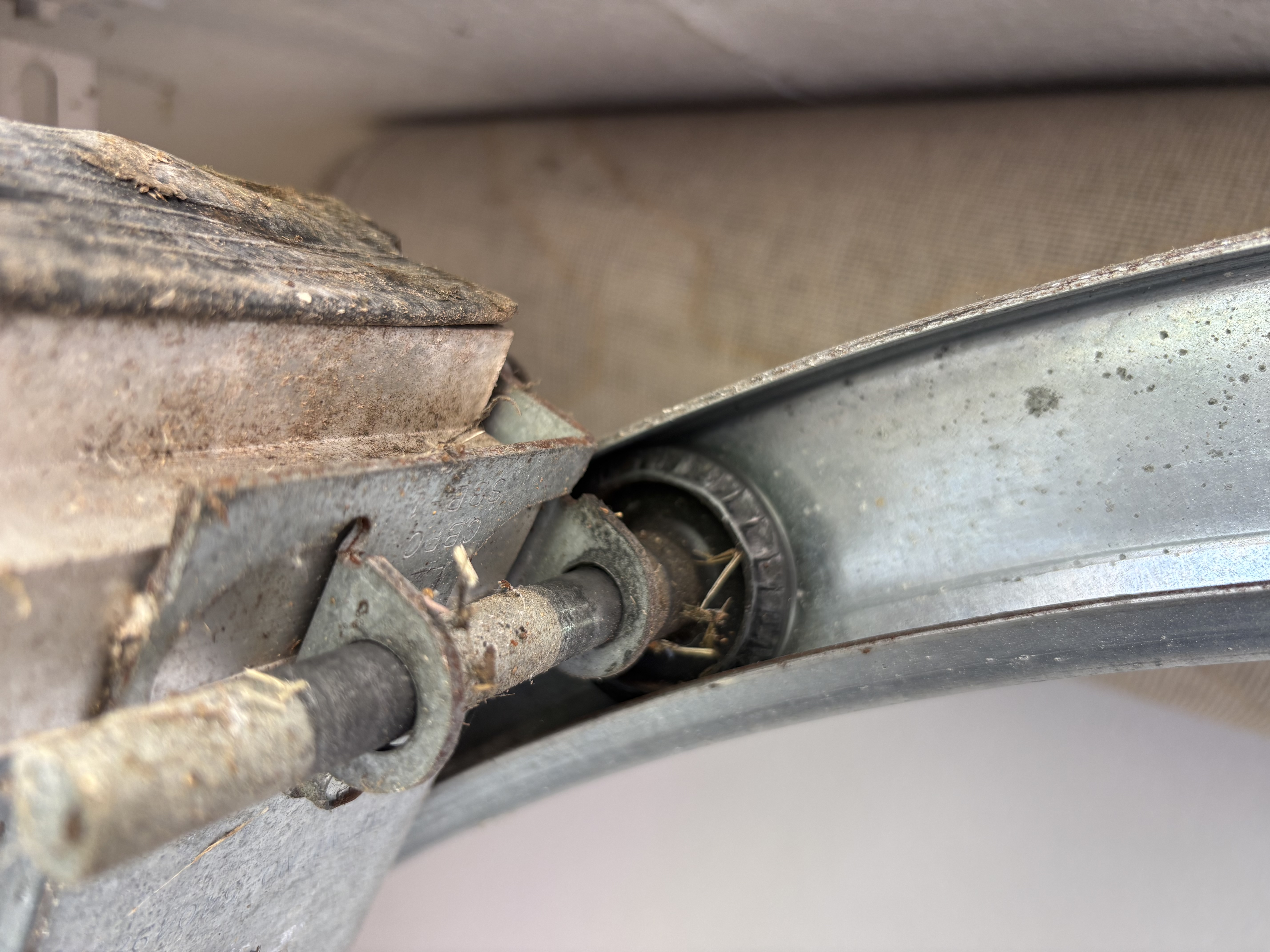 Worn and seized plastic garage door roller on an Austin TX door bearing exposed and packed with debris
